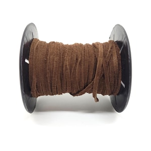 May include: A spool of brown suede leather cord. The cord is tightly wound around a black plastic spool. The suede has a soft, textured appearance. Ideal for jewelry making, crafting, and other creative projects.