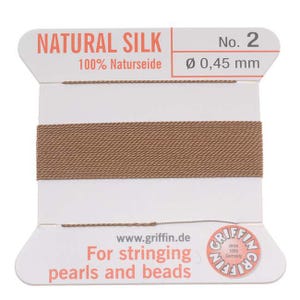 Op de afbeelding: Een spoel met natuurlijke zijden draad voor het rijgen van parels en kralen. De spoel is gelabeld met "Natural Silk 100% Naturseide" en "No. 2 Ø 0,45 mm".