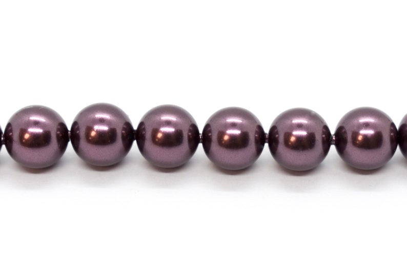 May include: A strand of dark purple round beads. The beads are smooth and shiny.