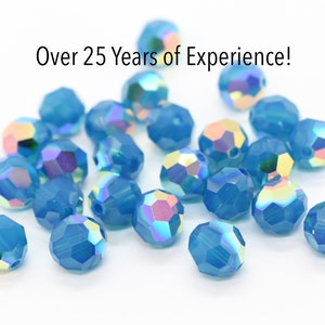 May include: A pile of light blue iridescent glass beads. The beads are round and have a faceted design.