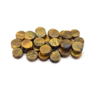 May include: A pile of round, brown and gold tiger's eye beads with a hole drilled through the centre of each bead.