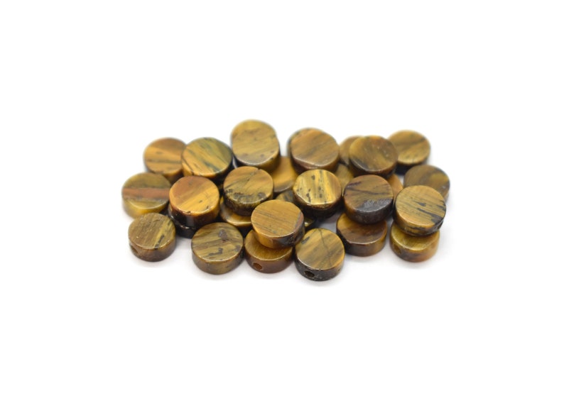 May include: A pile of round, brown and gold tiger's eye beads with a hole drilled through the centre of each bead.