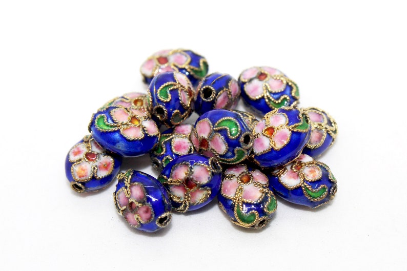 May include: A collection of oval-shaped beads with a blue enamel base and floral designs in pink, white, and green. The beads have a gold trim.