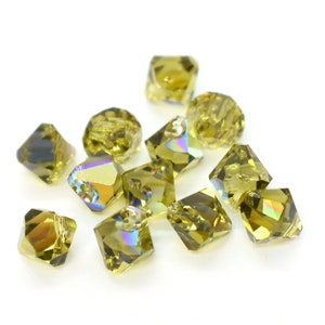 May include: A group of 12 iridescent green glass beads with a faceted square shape.