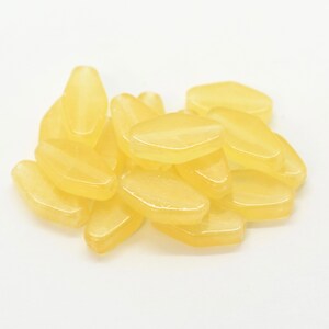 May include: A pile of yellow lemon-shaped sweets.
