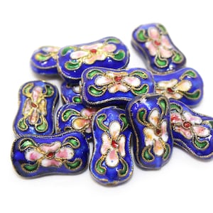 May include: A group of blue and gold enamel beads with floral designs. The beads are shaped like elongated ovals and have white, pink, and green accents.