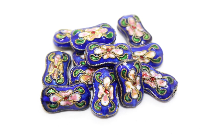 May include: A group of blue and gold enamel beads with floral designs. The beads are shaped like elongated ovals and have white, pink, and green accents.