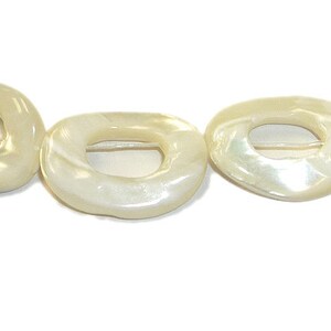 May include: A strand of white mother of pearl shell beads with a ring shape. The beads are smooth and have a slight iridescent sheen.