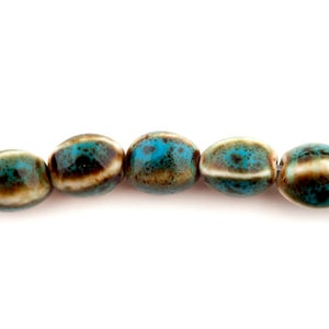 Peut inclure: Un brin de perles en céramique de forme ovale avec un motif marbré bleu et brun.