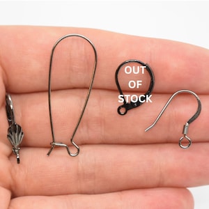 May include: Three different styles of earring hooks. The first is a silver-toned, teardrop-shaped hook. The second is a black, teardrop-shaped hook. The third is a silver-toned, leverback hook.