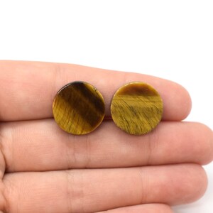 May include: Two round tiger's eye cabochons, one brown and gold, the other gold and brown, with a subtle shimmer.