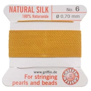 May include: A spool of natural silk thread for stringing pearls and beads. The spool is labelled "NATURAL SILK 100% Naturseide No. 6 Ø 0,70 mm" and "For stringing pearls and beads".