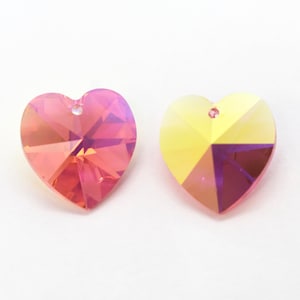 Puede incluir: Dos colgantes de cristal en forma de coraz&oacute;n, uno rosa y otro amarillo, con acabados iridiscentes.