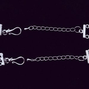 May include: Two silver-toned extender chains with lobster claw clasps and toggle clasps. Each chain is approximately 5 cm long.