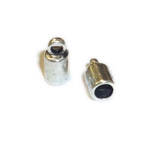 May include: Two silver metal end caps for cord or string. Each cap has a small loop at the top.