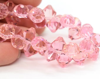 Può includere: Una collana di perline di vetro rosa sfaccettate. Le perline sono infilate su un filo trasparente e sono disposte in un motivo circolare.