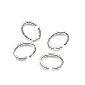 May include: Four silver oval jump rings, each with a slightly different angle, on a white background.