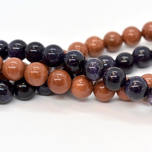 May include: A strand of brown and blue gemstone beads. The beads are round and have a speckled appearance.