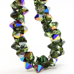 May include: A strand of dark green iridescent crystal beads. The beads are faceted and have a pointed shape.