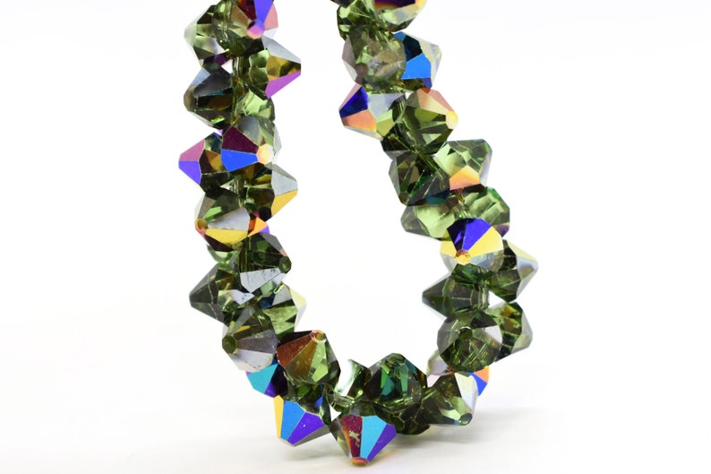 May include: A strand of dark green iridescent crystal beads. The beads are faceted and have a pointed shape.