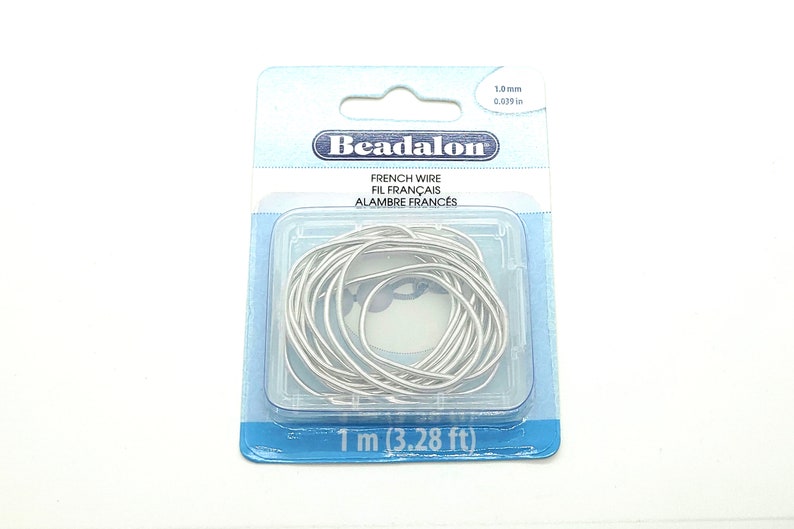 May include: A pack of silver French wire for beading. The pack is labelled "Beadalon French Wire Fil Fran&ccedil;ais Alambre Franc&eacute;s" and contains 1 metre (3.28 feet) of wire with a diameter of 1.0 mm (0.039 inches).