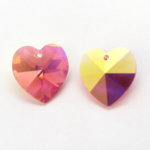 Puede incluir: Dos abalorios de cristal en forma de coraz&oacute;n, uno de color iridiscente rosa y morado y el otro de color iridiscente amarillo y morado.