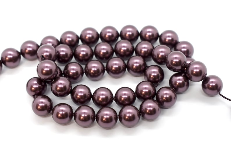 May include: A strand of dark purple faux pearl beads. The beads are round and have a smooth, glossy finish.