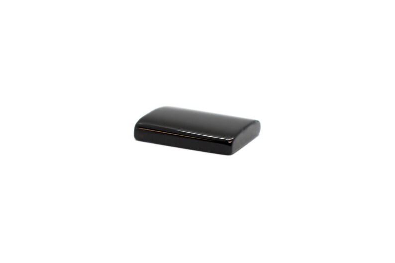 Peut inclure: Une batterie rectangulaire noire avec des bords arrondis.