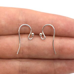 May include: A pair of silver earring hooks with a small ball at the top of each hook.