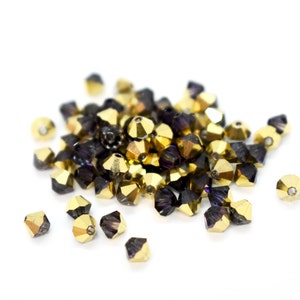 May include: A pile of gold and purple glass beads. The beads are faceted and have a shiny finish.