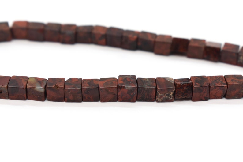 May include: A strand of brown and white jasper beads, each bead is a cube shape.