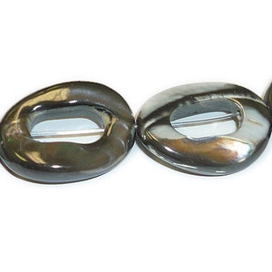 May include: A strand of black and white oval-shaped shell beads with a hole in the center of each bead.