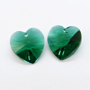 Puede incluir: Dos colgantes de cristal verde en forma de coraz&oacute;n con un agujero en la parte superior para colgar.