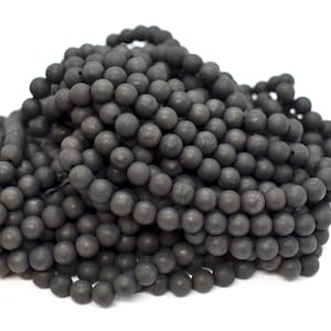 Op de afbeelding: Een stapel zwarte ronde kralen, waarschijnlijk gemaakt van onyx of obsidiaan, voor het maken van sieraden.