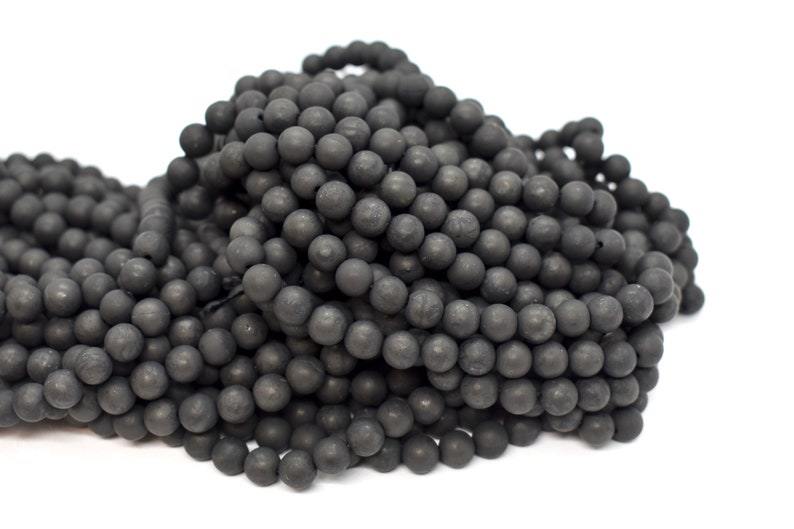Op de afbeelding: Een stapel zwarte ronde kralen, waarschijnlijk gemaakt van onyx of obsidiaan, voor het maken van sieraden.