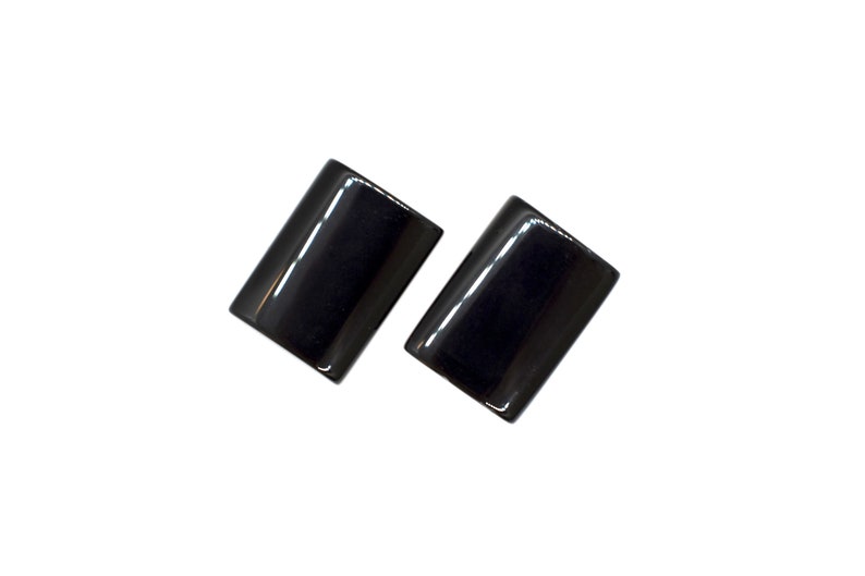 Peut inclure: Une paire de boucles d'oreilles rectangulaires noires. Les boucles d'oreilles sont en mat&eacute;riau lisse et brillant.