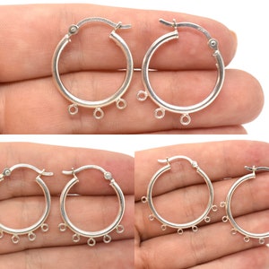 May include: Silver hoop earrings with three dangling loops on each earring. The hoops are about 1 inch in diameter.