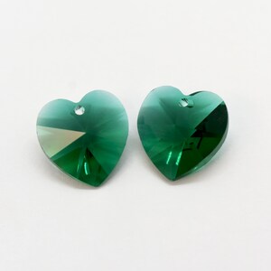 Puede incluir: Dos colgantes de cristal en forma de coraz&oacute;n verde con un agujero en la parte superior para colgar.