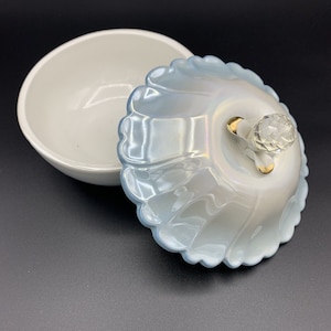 May include: A white ceramic trinket box with a blue iridescent lid. The lid has a scalloped edge and a crystal knob.