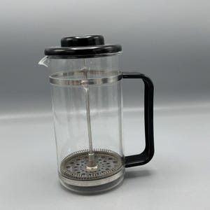 以下が含まれることがあります： 黒い蓋とハンドルが付いた透明なガラス製のフレンチプレスコーヒーメーカー。 プレスにはステンレス鋼のフィルターとシルバーのバンドが付いています。 コーヒーを淹れるように設計されています。