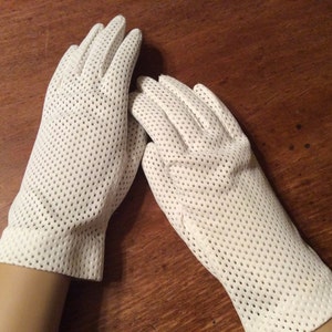 Könnte beinhalten: Ein Paar weiße Netzhandschuhe mit einem gepunkteten Muster.