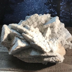 May include: A large, white, crystalline cluster of selenite. The selenite is a natural mineral with a smooth, glassy texture. The cluster is composed of many individual crystals that are intergrown together.