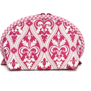 May include: A semi-circular zippered pouch featuring a vibrant hot pink and white damask pattern. The curved top edge is finished with a pink and white gingham check fabric trim, providing a distinct contrast to the ornate floral motif.