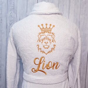 May include: White bathrobe with a gold embroidered lion wearing a crown and the word "Lion" underneath.