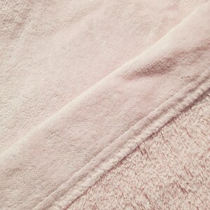 K&ouml;nnte beinhalten: Nahaufnahme eines weichen, rosa Handtuchs mit einer diagonal verlaufenden Naht.