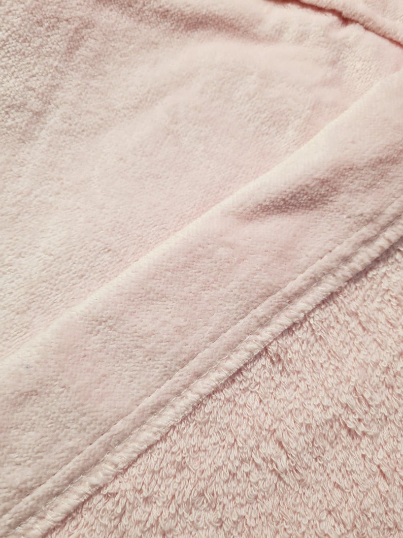K&ouml;nnte beinhalten: Nahaufnahme eines weichen, rosa Handtuchs mit einer diagonal verlaufenden Naht.