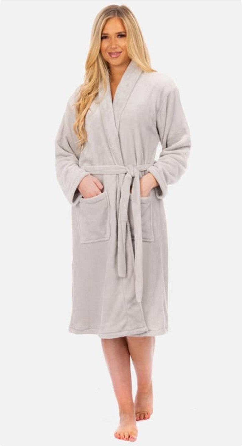 May include: A soft, gray robe with a shawl collar and a tie belt. The robe has two pockets and is made of a plush material.
