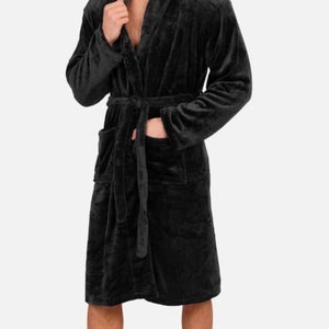 May include: A black plush robe with a shawl collar and a tie belt. The robe has two pockets on the front.