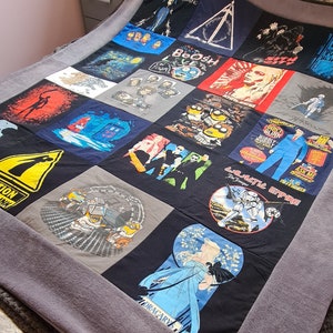 May include: A patchwork quilt made from various t-shirts featuring different designs and text. The quilt is made of black, blue, grey, red, and white fabric. The text on the t-shirts includes "Winter is Coming", "Boosh", "Don't Blink", "Galactic Empire", "The Trooper", and "Ask Me If It Is Defended".