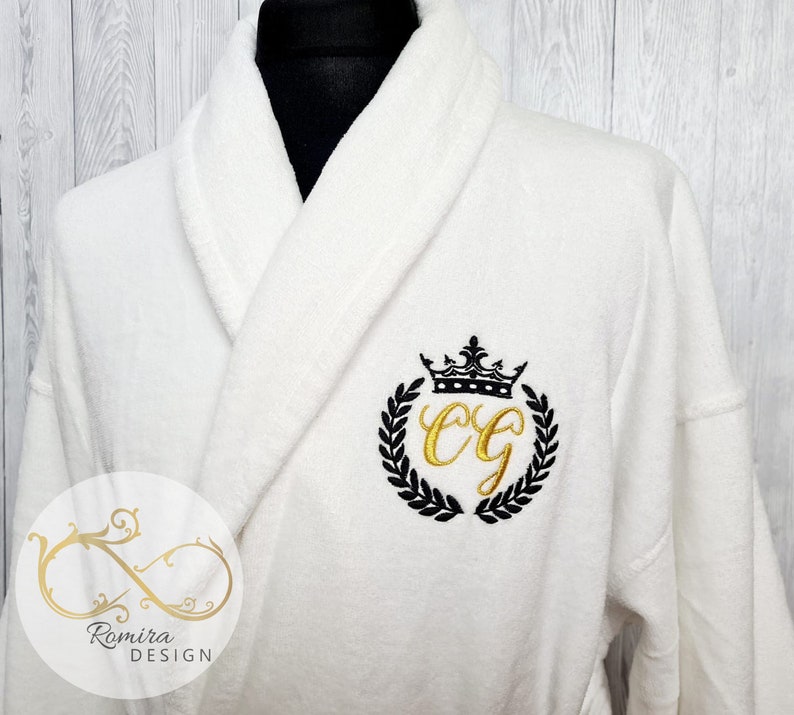 May include: White bathrobe with a black and gold embroidered monogram with a crown and laurel wreath. The monogram is "CG".